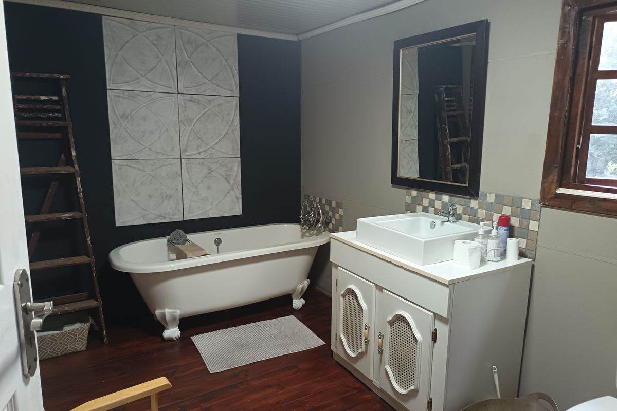 A bathroom featuring a classic clawfoot bathtub, a vanity with a vessel sink, and decorative wall tiling.