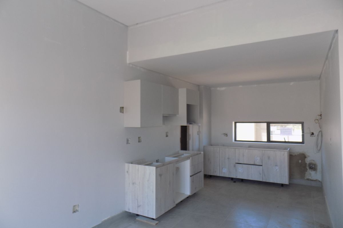 An unfinished kitchen area featuring light wood-look cabinetry, tiled flooring, and neutral walls, currently undergoing renovation or final installation.