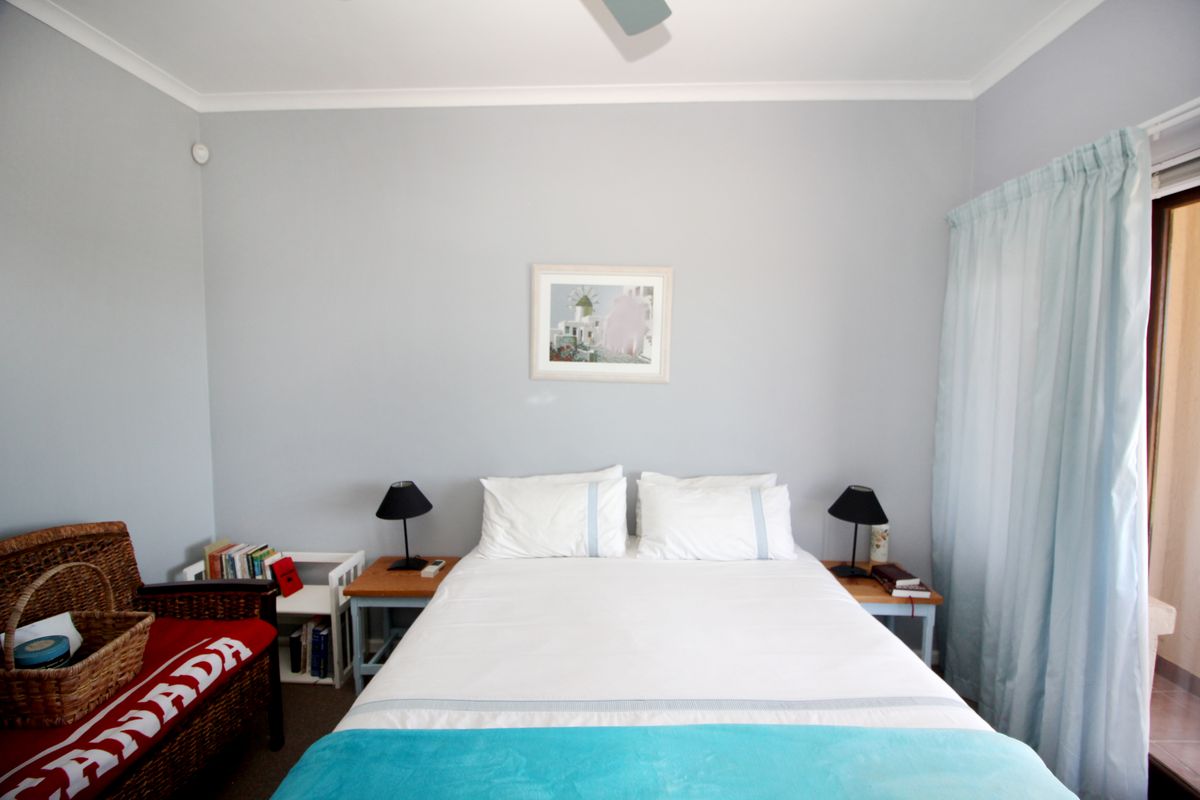 A well-maintained bedroom featuring neutral wall tones, a ceiling fan, and direct access to an outdoor area through a sliding glass door.