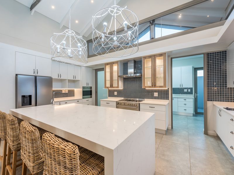 Modern kitchen featuring a large central island with stone countertops, high-end cabinetry, integrated appliances, and a separate scullery area with matching finishes.