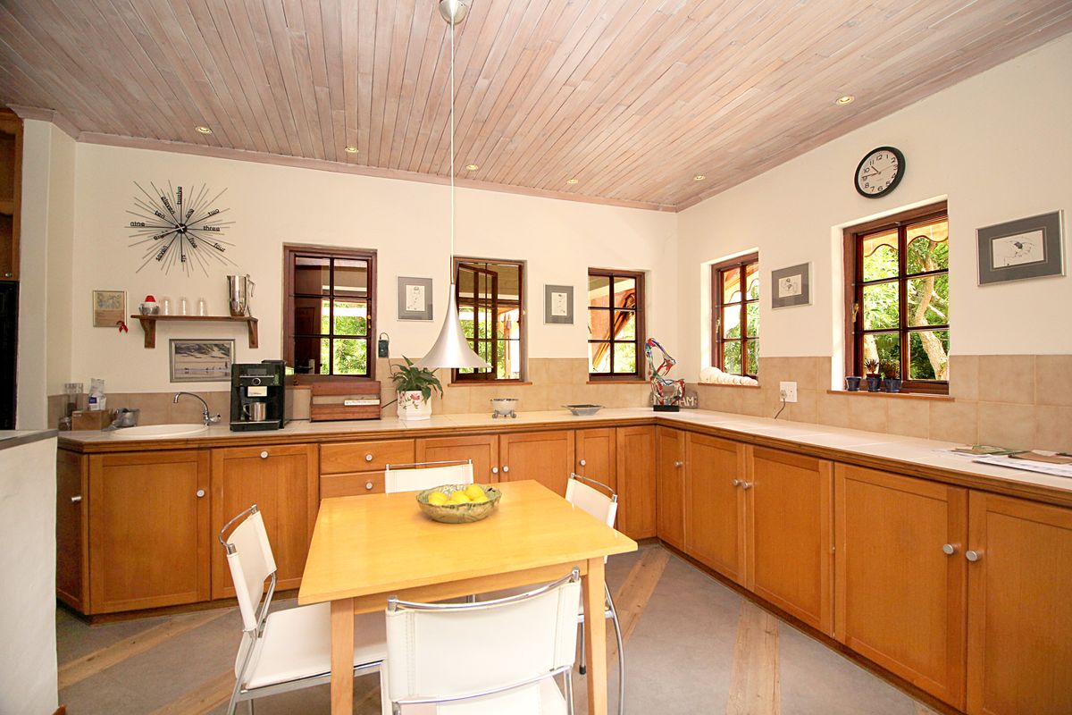 A spacious kitchen featuring timber cabinetry, tiled countertops, and a distinctive timber-paneled ceiling with recessed lighting.