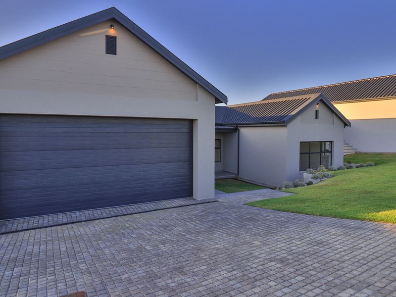 Modern residential exterior featuring a double garage, paved driveway, and well-maintained lawn under a clear sky.