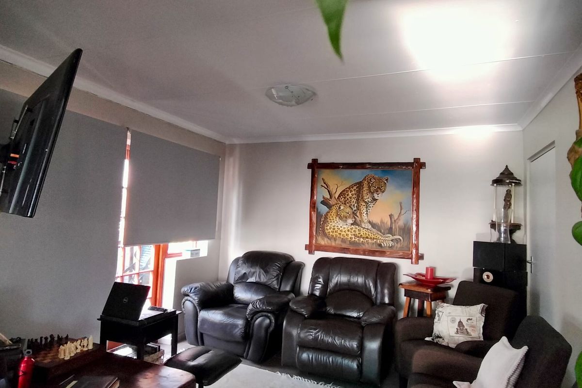 A comfortable living room featuring tiled flooring, roller blinds, and a cove ceiling, providing a functional and well-lit space for relaxation.