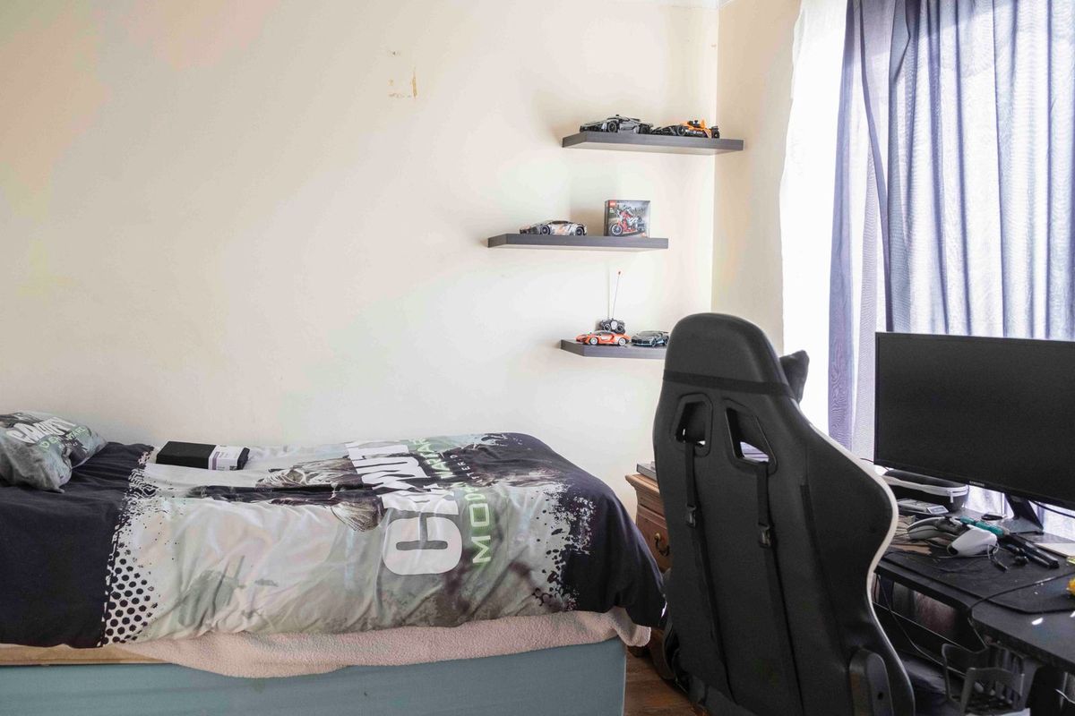 A functional bedroom featuring built-in floating wall shelves and natural light from a window.