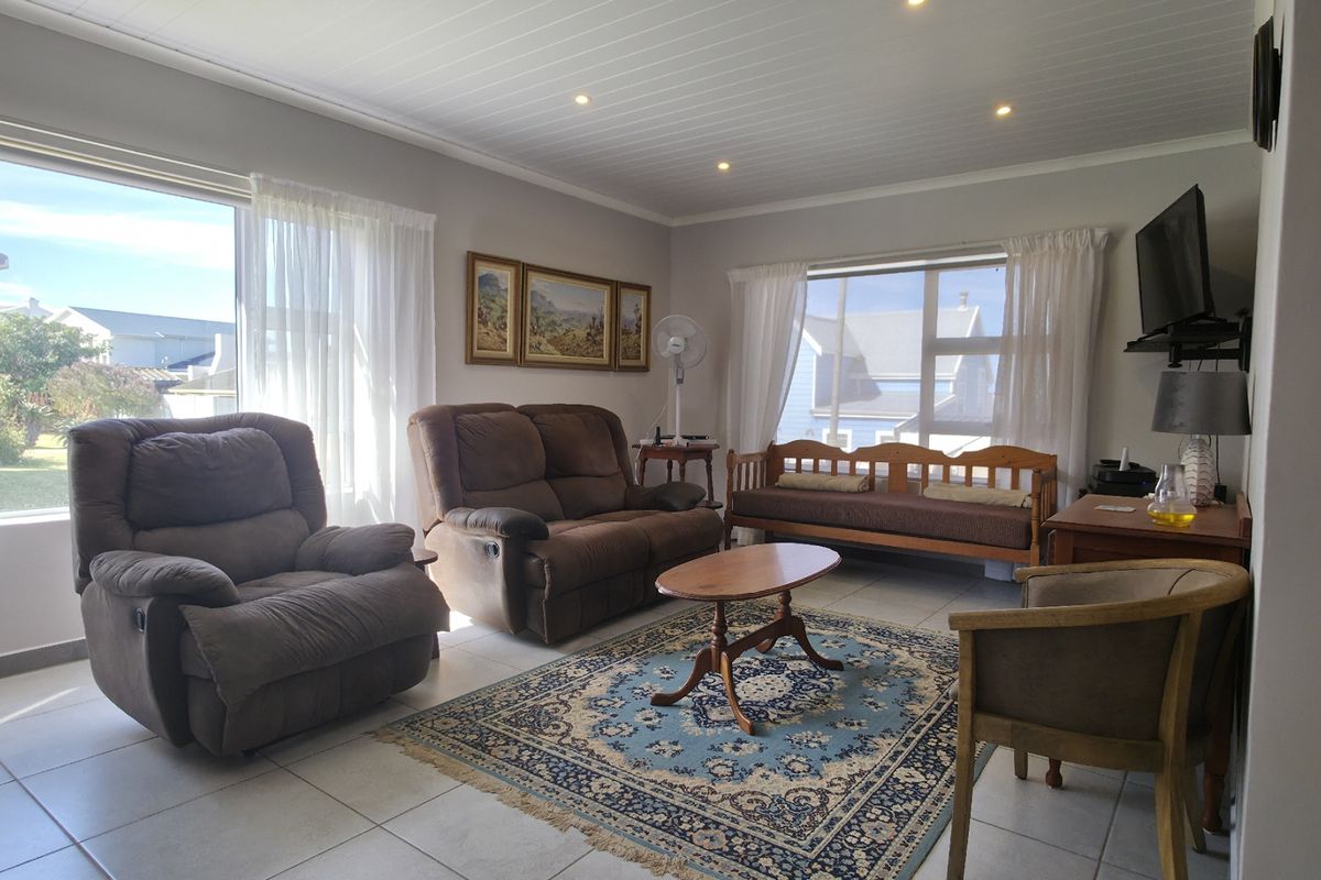 A bright living room featuring large windows, tiled flooring, and recessed ceiling lighting, offering a comfortable and functional space.