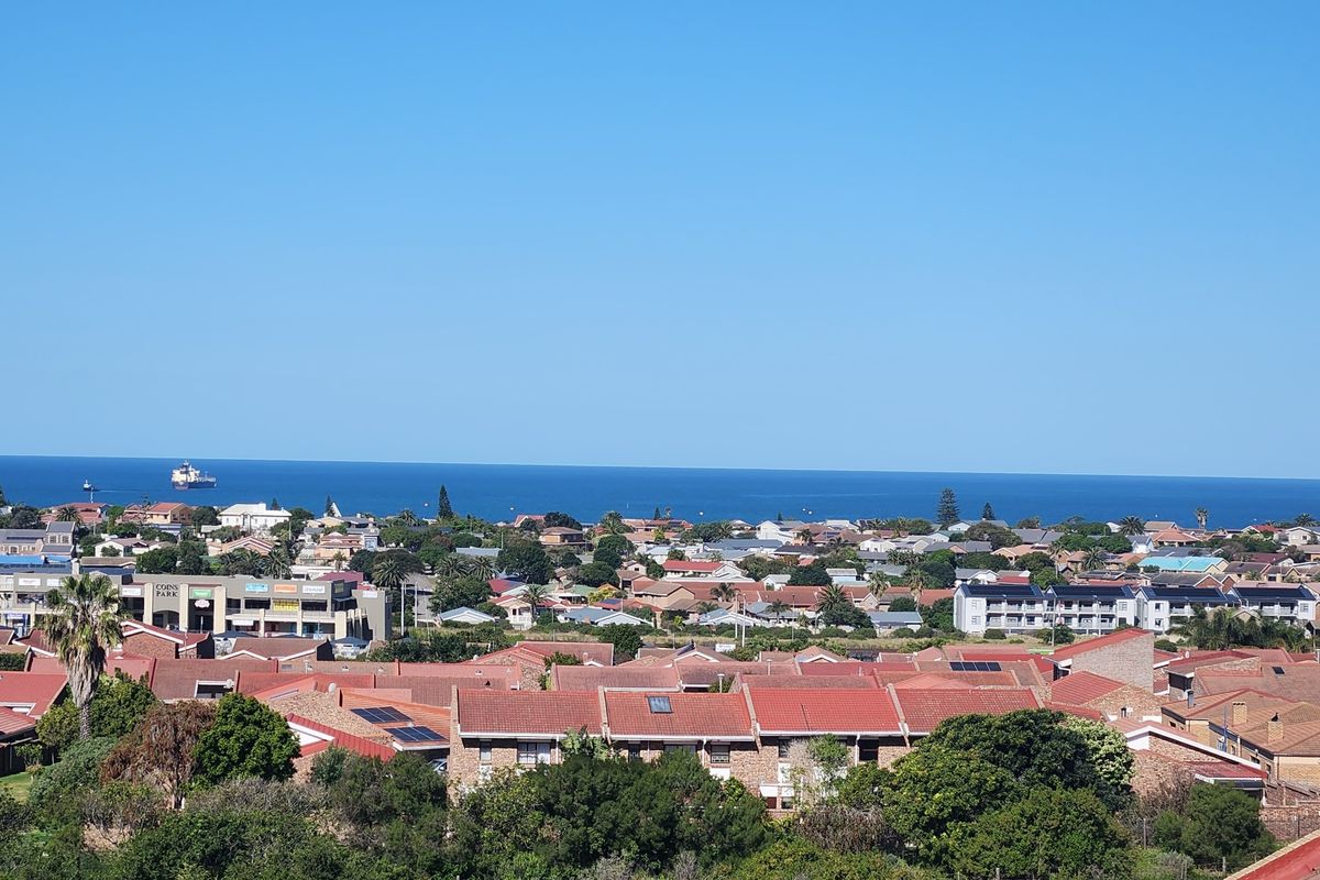 An elevated panoramic view overlooking a residential neighborhood with a clear view of the ocean in the distance.