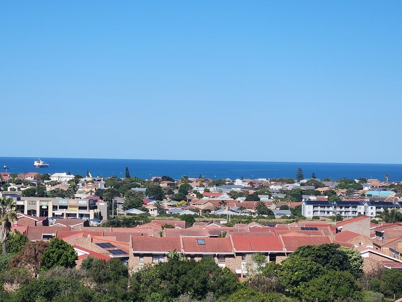 An elevated panoramic view overlooking a residential neighborhood with a clear view of the ocean in the distance.