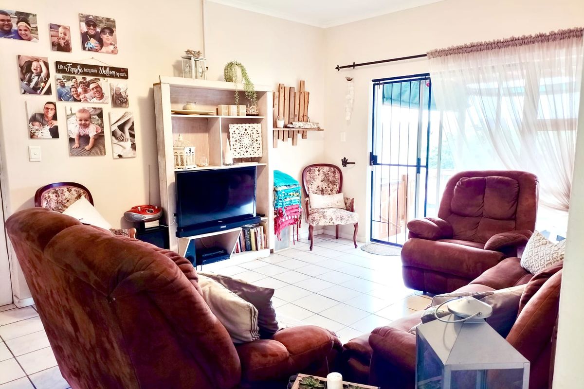 A comfortable living room featuring tiled flooring and a sliding glass door with a security gate, providing access to the outdoor area.