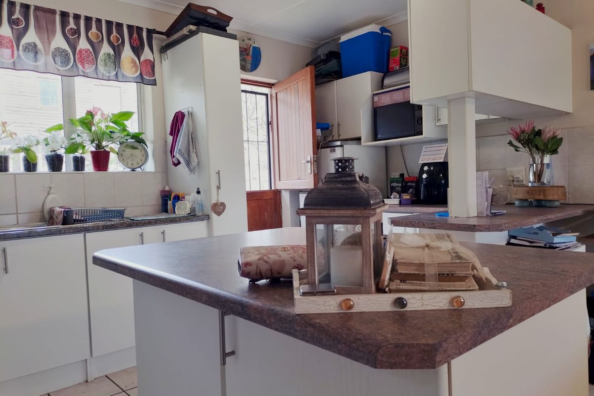 A functional kitchen featuring laminate countertops, ample built-in cabinetry, a double sink, and a tiled backsplash with direct access to the exterior.