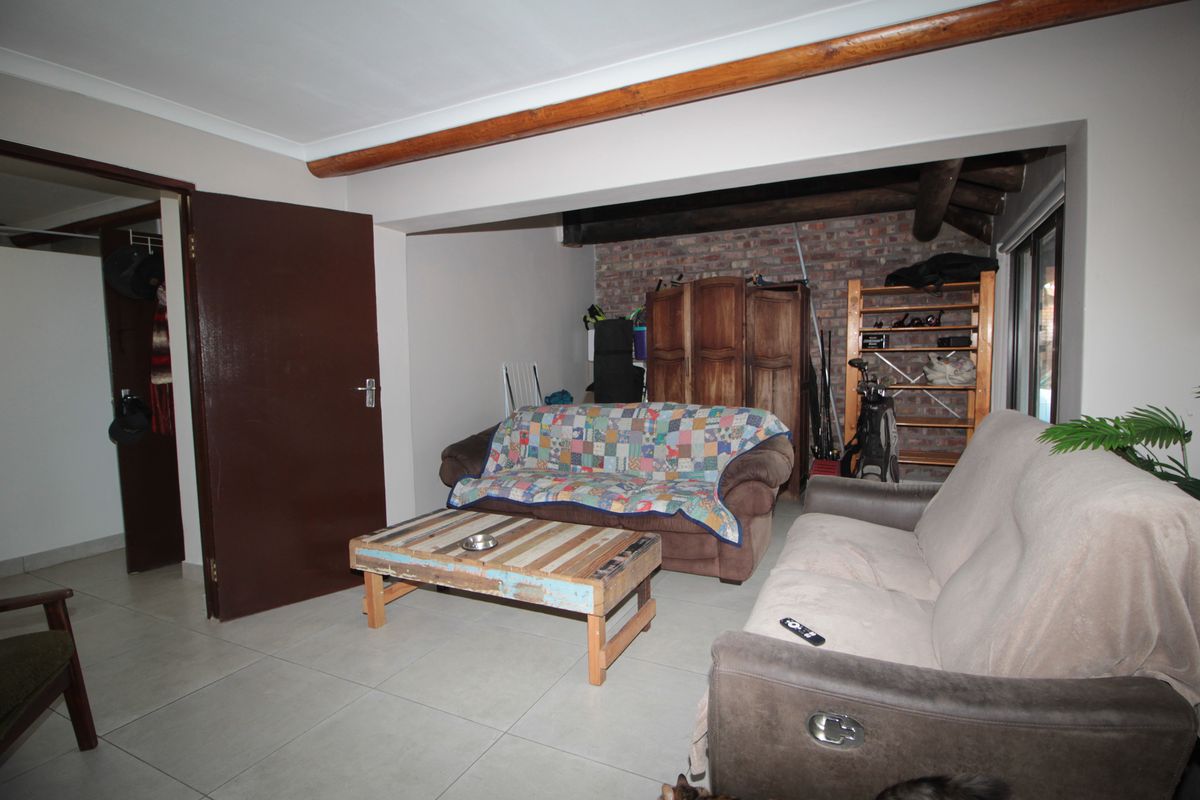 Living room featuring exposed brickwork, timber ceiling beams, and neutral tiled flooring, offering a rustic aesthetic with potential for modern updates.