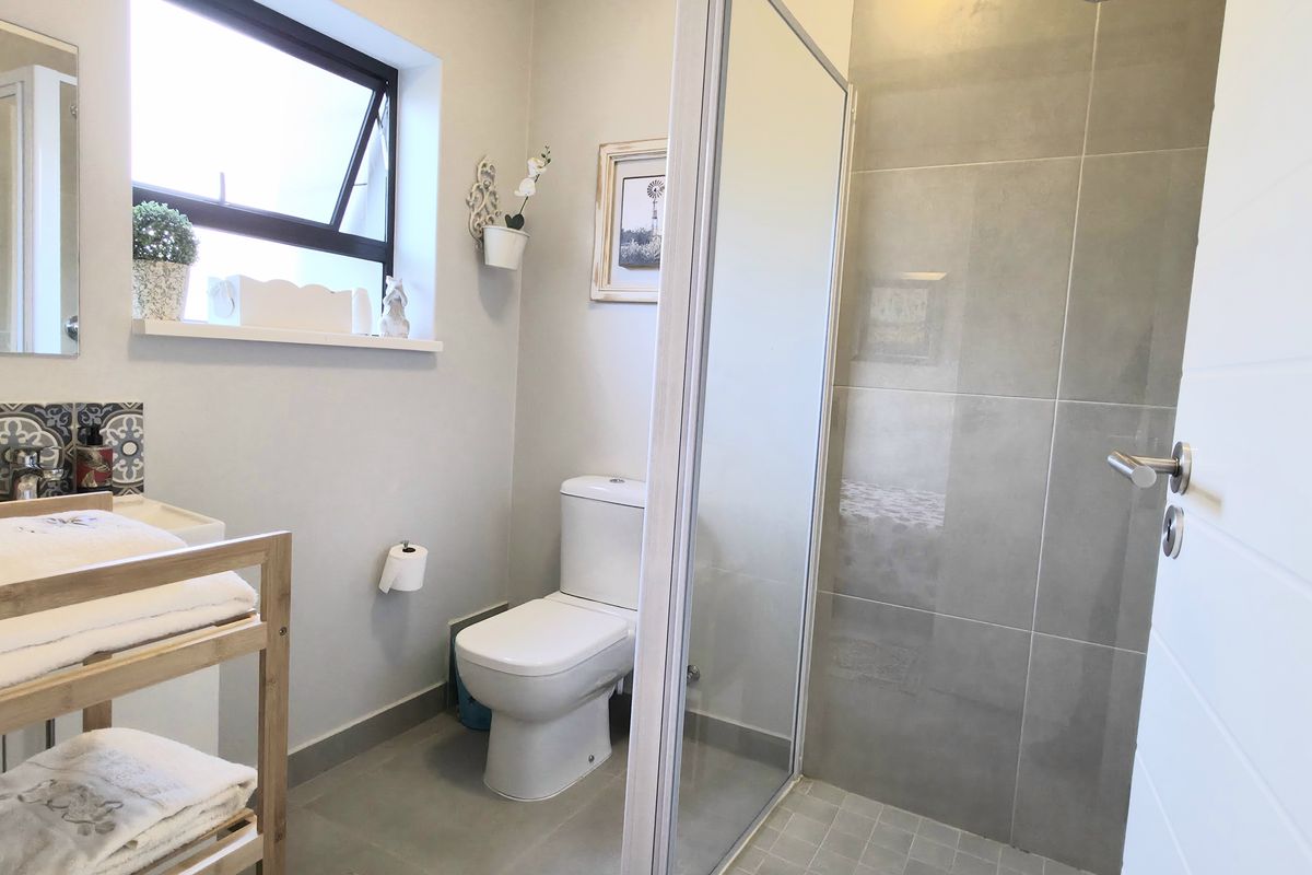 A modern bathroom featuring a glass-enclosed shower, a wall-mounted toilet, and a vanity basin with decorative tiled backsplash.