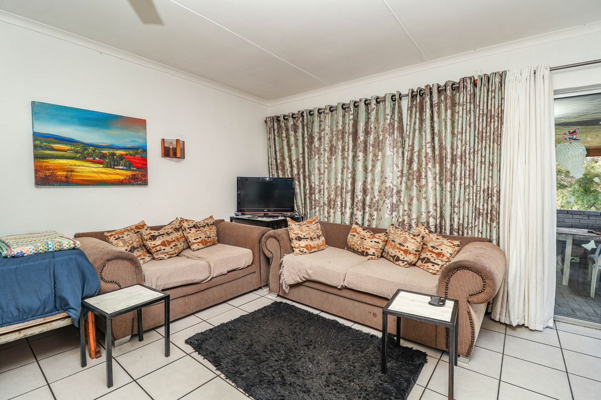A living room featuring ceramic floor tiles, a ceiling fan, and sliding glass doors providing access to an outdoor patio area.