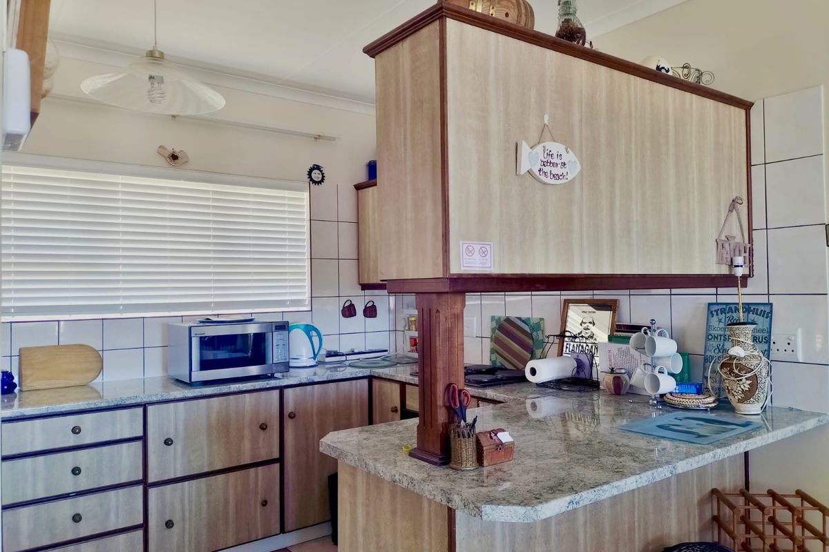 A functional kitchen featuring wood-look cabinetry, granite-style countertops, tiled splashbacks, and a breakfast nook counter, offering a practical layout for daily meal preparation.