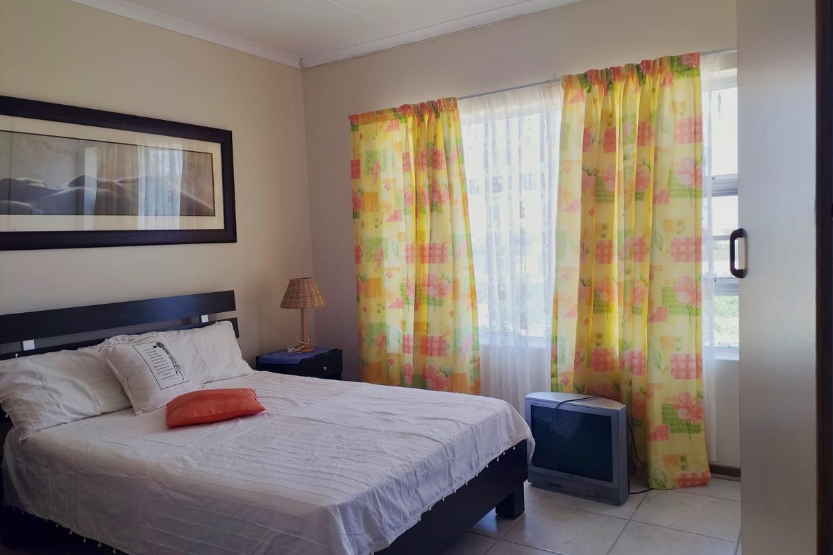 A standard bedroom featuring tiled flooring and a large window with natural light.