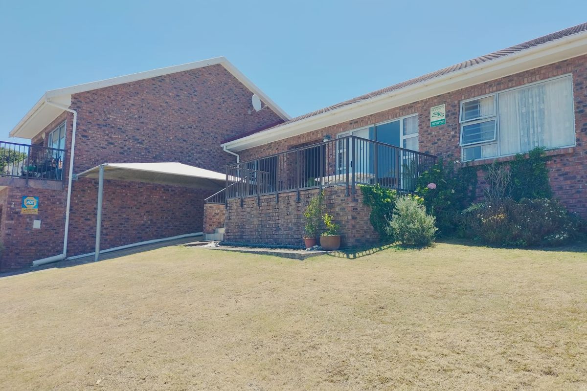 Exterior view of a brick duet property featuring a raised patio, metal balustrades, and a covered carport area.