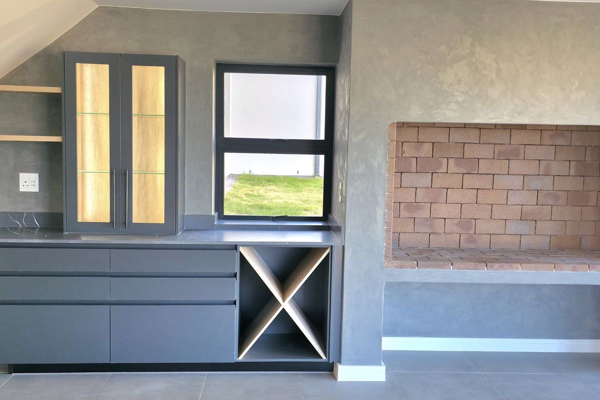 Modern entertainment area featuring built-in cabinetry, stone countertops, integrated wine storage, and a traditional brick-lined indoor fireplace.