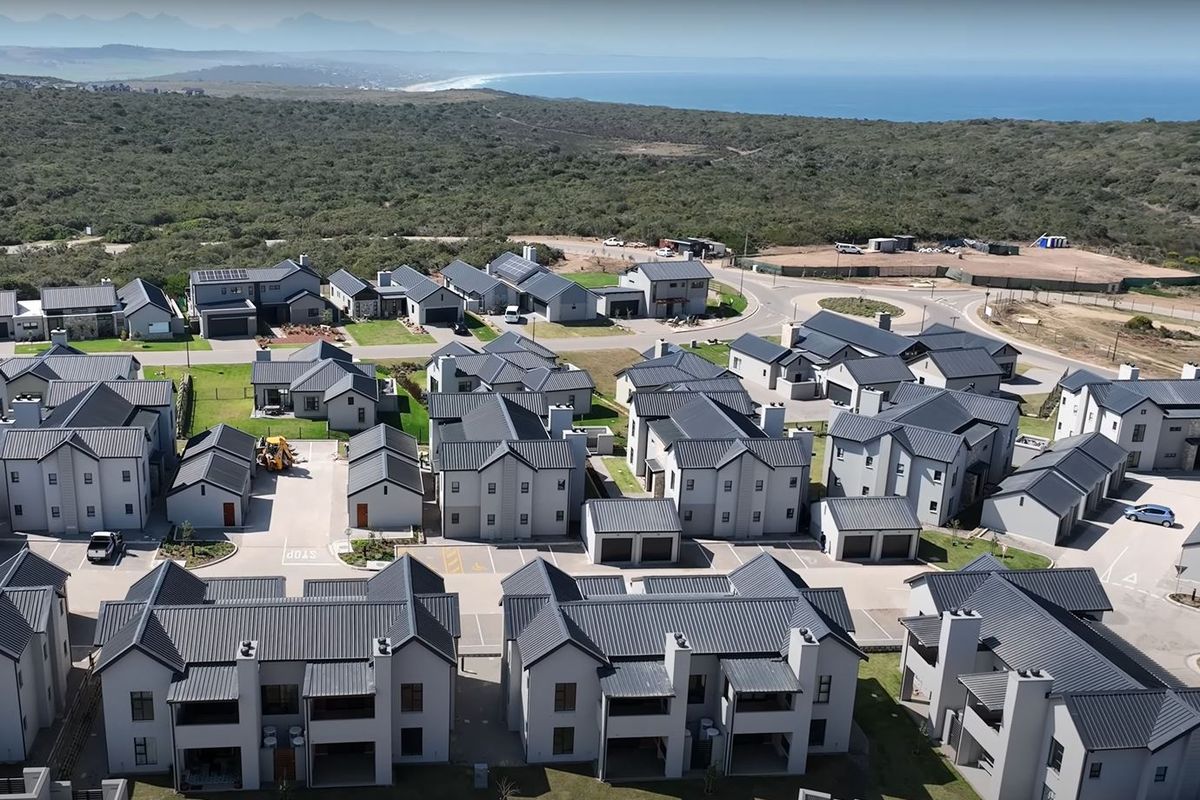 Aerial view of a modern residential estate featuring contemporary apartment blocks with dark metal roofing and paved access roads.