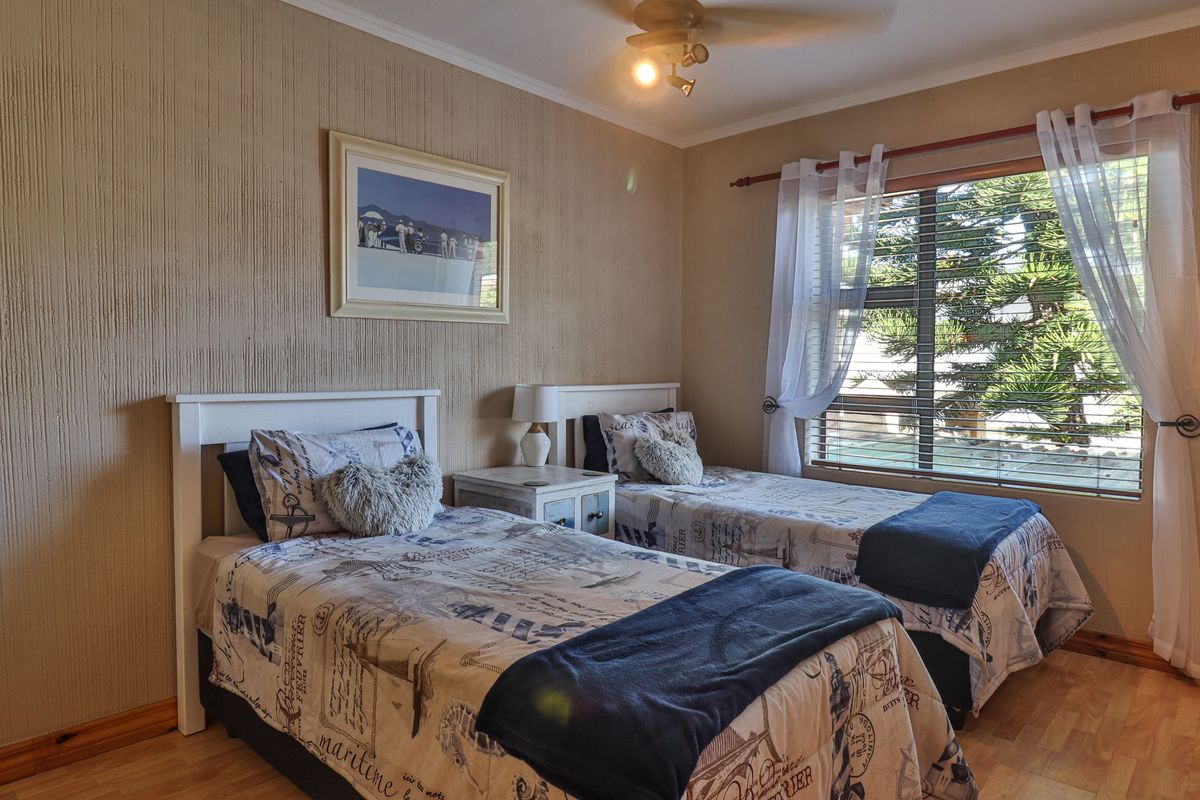 A cozy bedroom featuring laminate flooring, a ceiling fan, and window blinds, providing a comfortable space for rest.