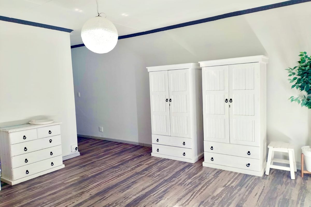 A bedroom featuring laminate flooring and a sloped ceiling, providing a clean and neutral space.