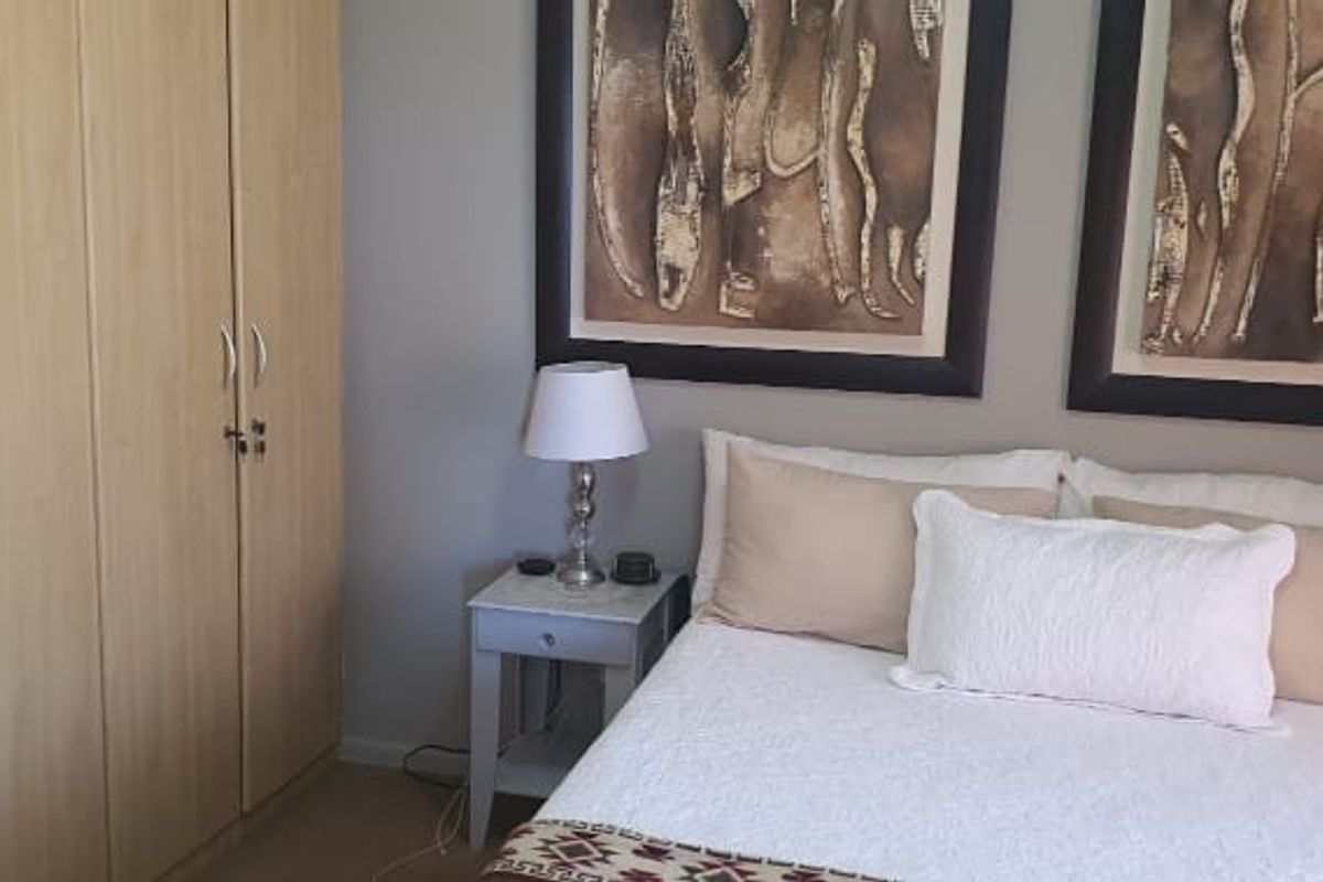 A well-maintained bedroom featuring built-in wooden cupboards and neutral wall finishes, providing a clean and functional living space.