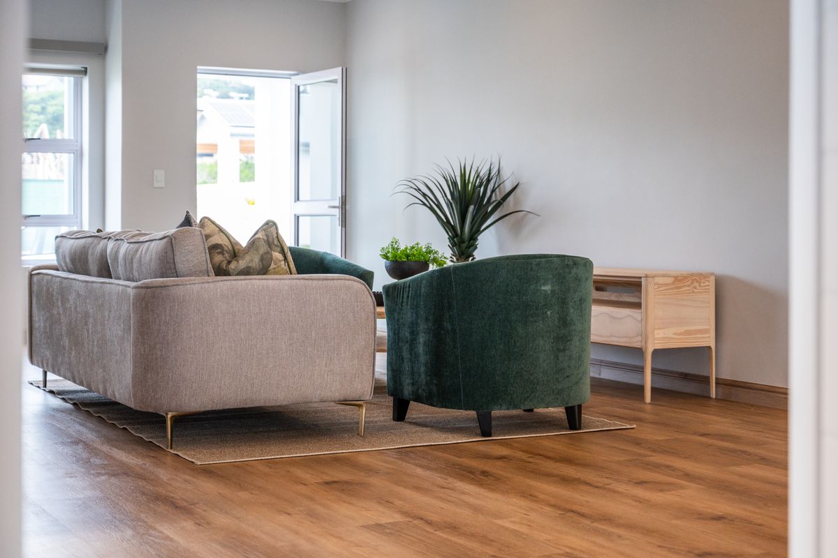 A bright and modern living area featuring wood-look flooring and direct access to an outdoor space through a glass door.