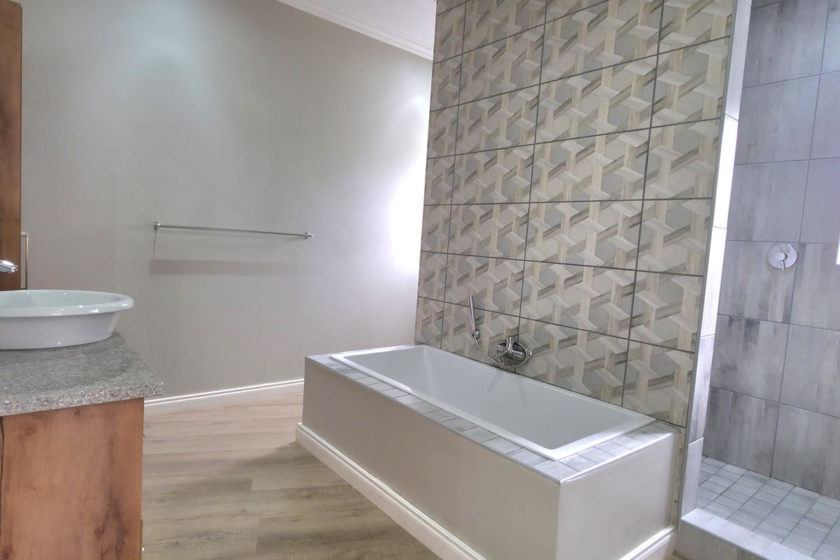 Modern bathroom featuring a vessel sink vanity, a tiled bathtub, and a separate walk-in shower with contemporary wall tiling.