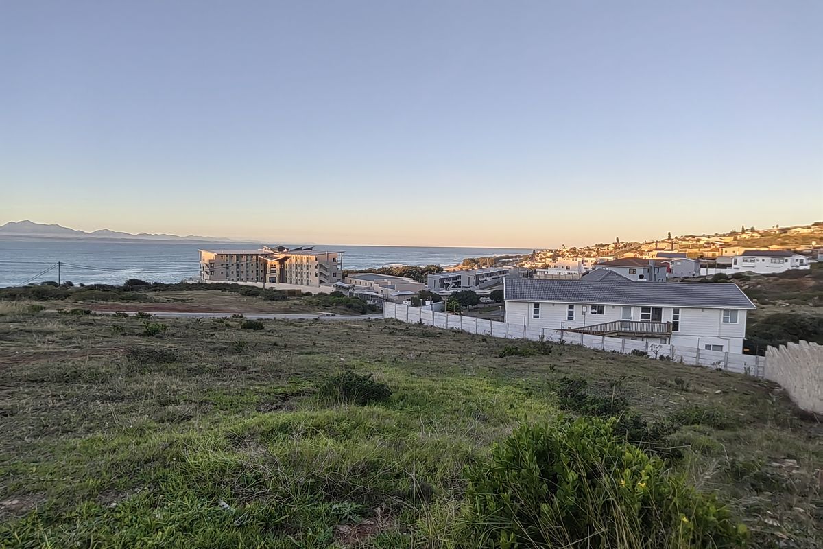 A scenic elevated view overlooking a coastal residential area with ocean vistas and distant mountain ranges.