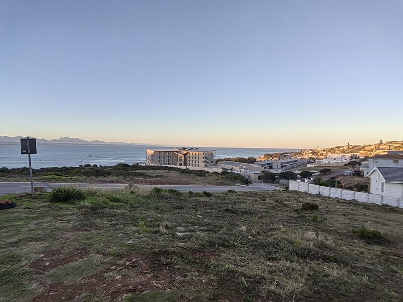 A scenic elevated view overlooking the coastline, nearby residential developments, and the ocean horizon.