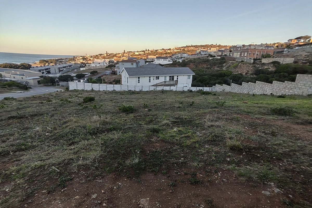 Elevated view overlooking a residential neighborhood, coastal landscape, and surrounding properties from a vacant residential plot.