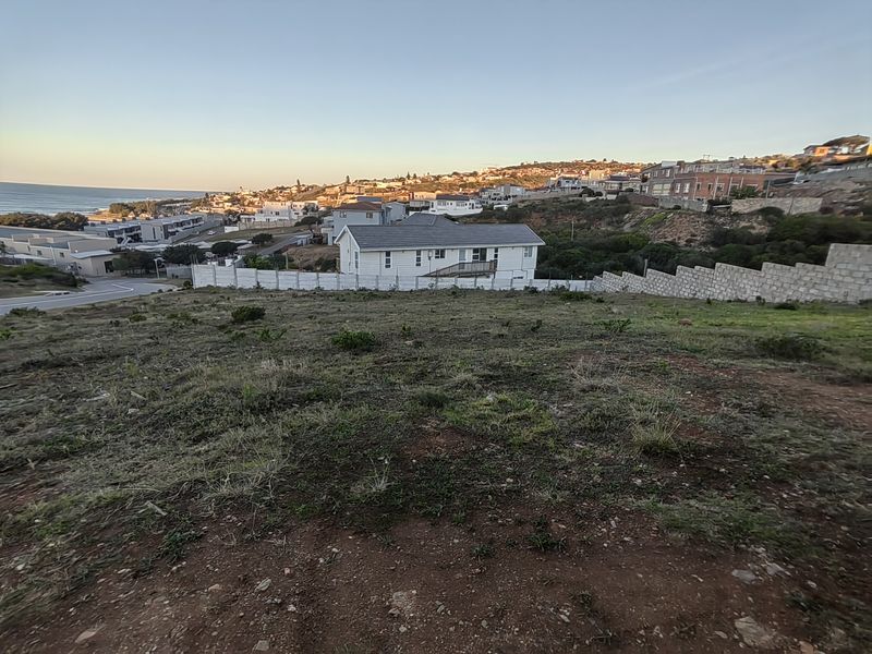 Elevated view overlooking a residential neighborhood, coastal landscape, and surrounding properties from a vacant residential plot.