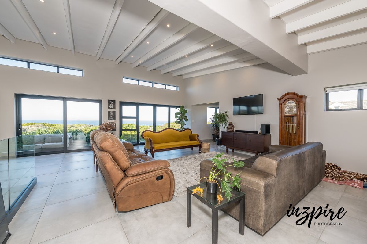 Spacious living room featuring high exposed beam ceilings, large format floor tiles, and expansive sliding glass doors offering natural light and scenic views.