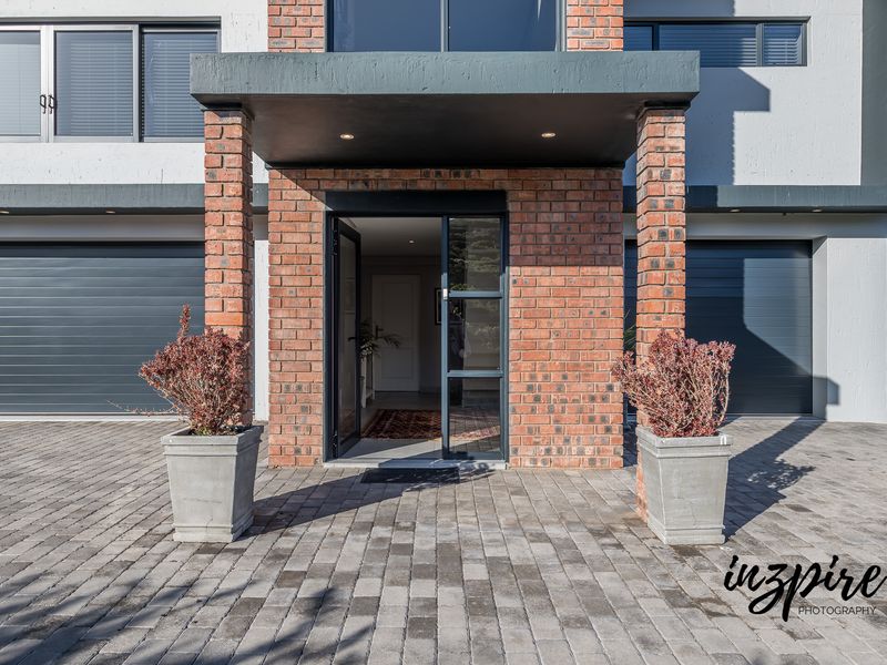 Modern front entrance featuring a brick facade, covered porch, and double garage doors with a paved driveway.
