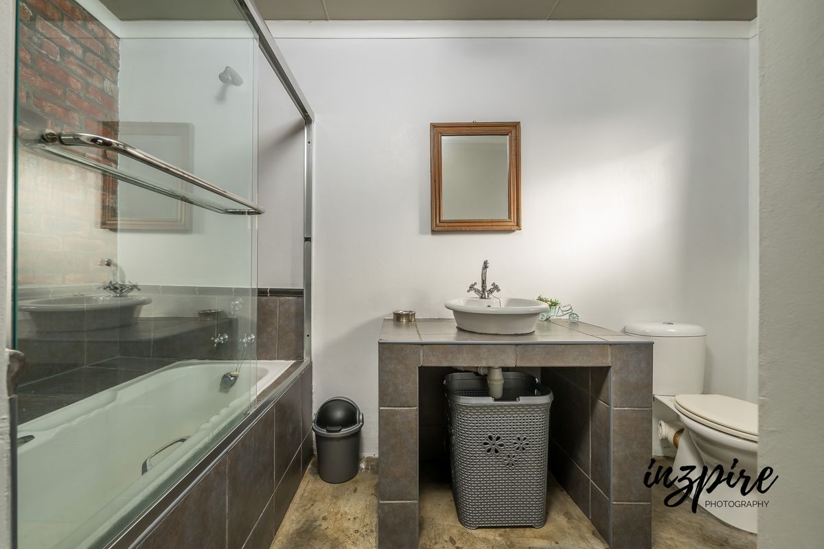 A functional bathroom featuring a tiled vanity with vessel sink, a combined shower and bathtub with glass screen, and a standard toilet.