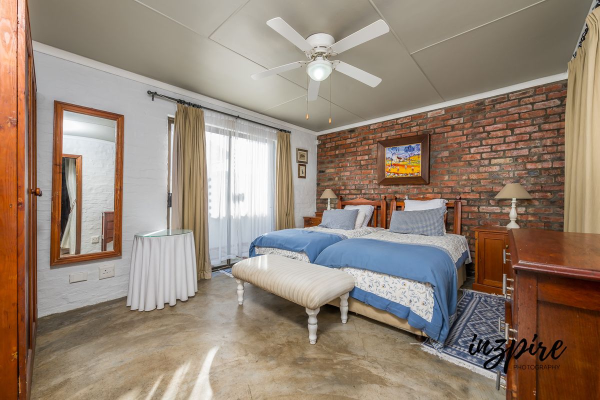 A bedroom featuring an exposed brick feature wall, concrete flooring, a ceiling fan, and sliding glass doors providing access to the exterior.