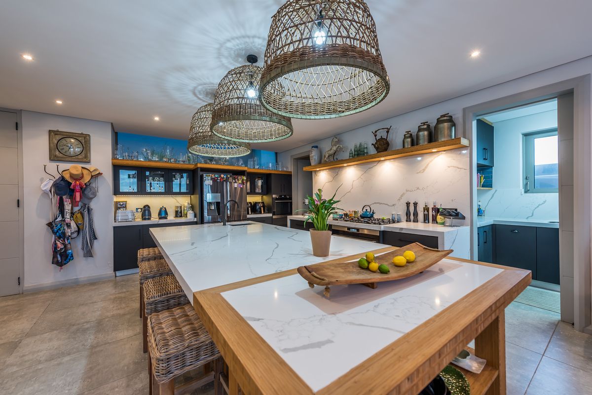 Modern kitchen featuring a large central island with stone countertops, integrated cabinetry, and a separate scullery area.