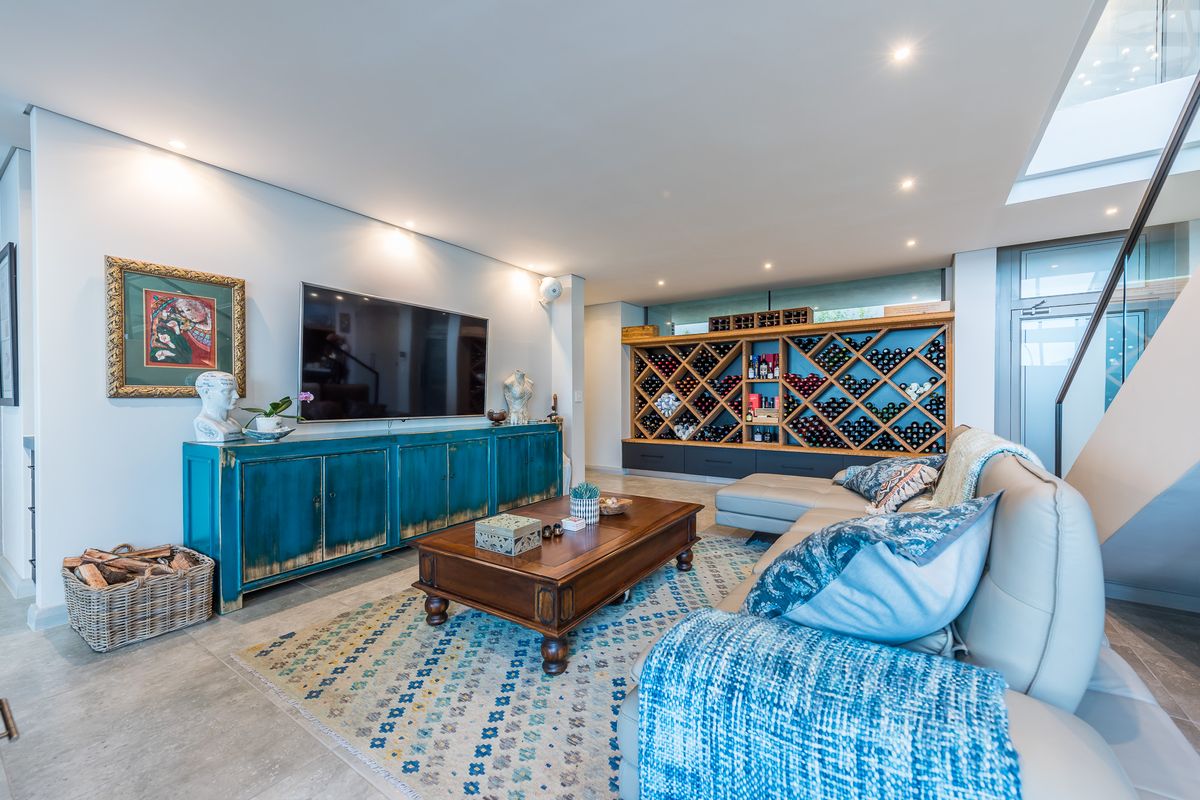 A modern living room featuring a built-in wooden wine rack, recessed ceiling lighting, and tiled flooring, creating a sophisticated and functional entertainment space.