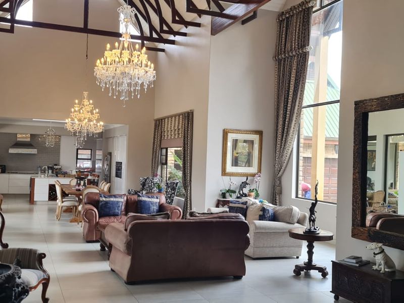 Spacious open-plan living area featuring high vaulted ceilings with exposed timber trusses, large windows, and a seamless flow into the modern kitchen.