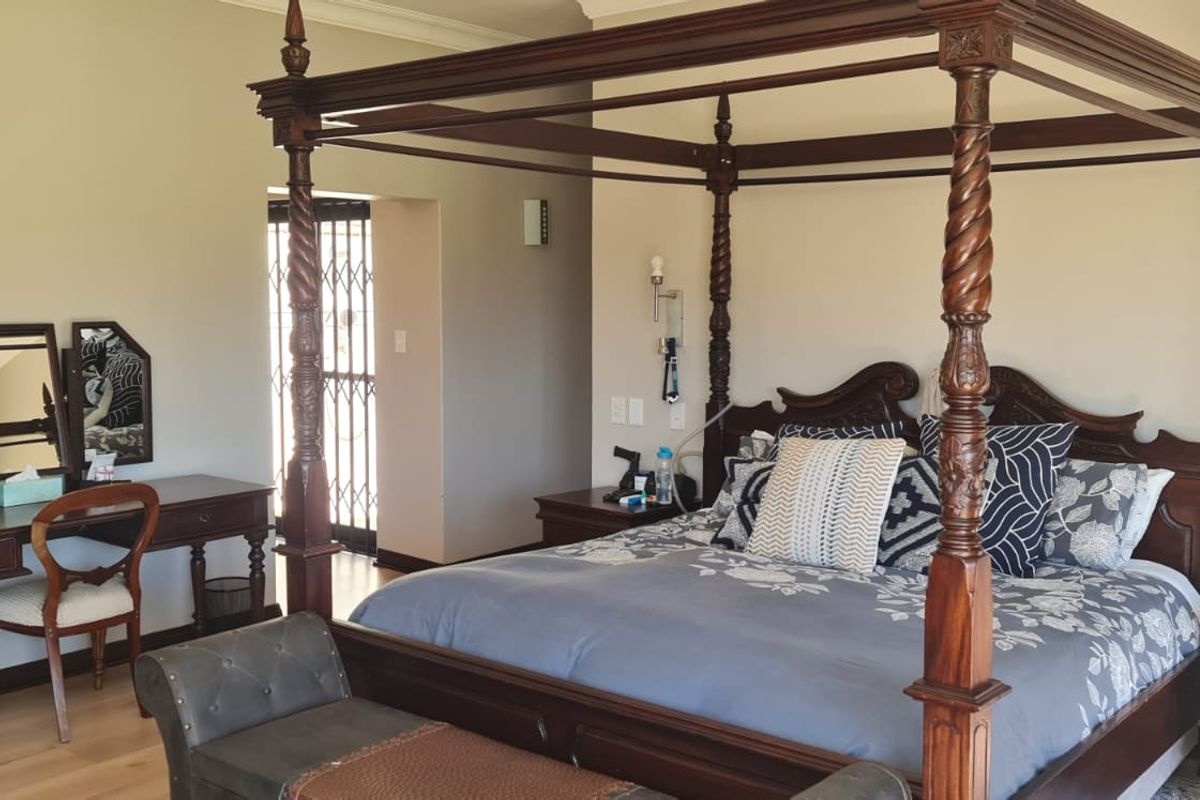 Spacious bedroom featuring laminate flooring, neutral wall tones, and a secure access point with a metal security gate.