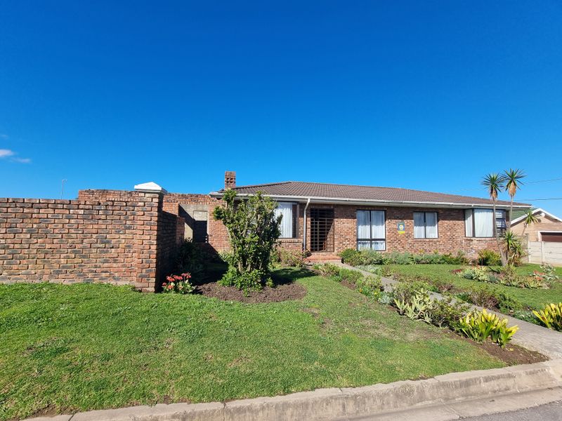 Front elevation of a single-story brick house featuring a tiled roof, security gate, and established front garden with a brick boundary wall.