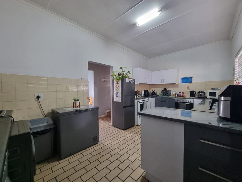 A functional kitchen featuring tiled flooring, a tiled backsplash, built-in cabinetry, and integrated cooking appliances, offering a practical layout for daily use.