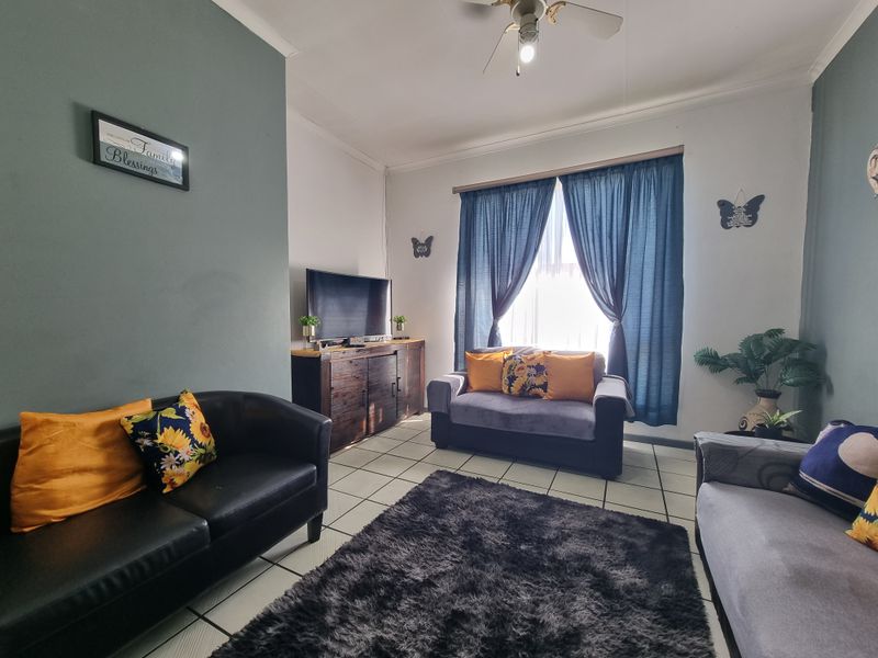 A comfortable living room featuring tiled flooring and a ceiling fan, providing a functional and well-lit space for relaxation.