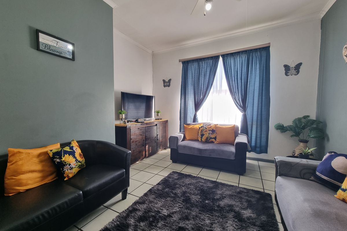 A comfortable living room featuring tiled flooring and a ceiling fan, providing a functional and well-lit space for relaxation.