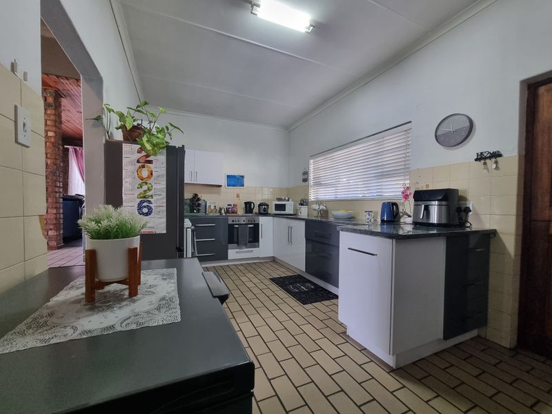 A functional kitchen featuring two-tone cabinetry, tiled flooring, and a tiled backsplash, offering a practical layout with integrated cooking appliances.