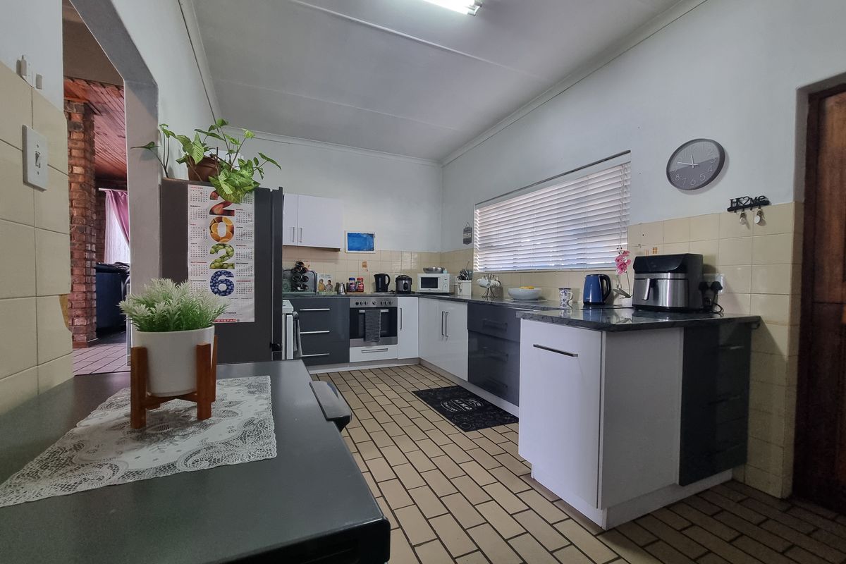 A functional kitchen featuring two-tone cabinetry, tiled flooring, and a tiled backsplash, offering a practical layout with integrated cooking appliances.