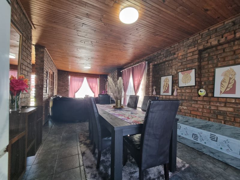 Open plan dining and living area featuring rustic exposed brick walls and a warm timber tongue and groove ceiling.