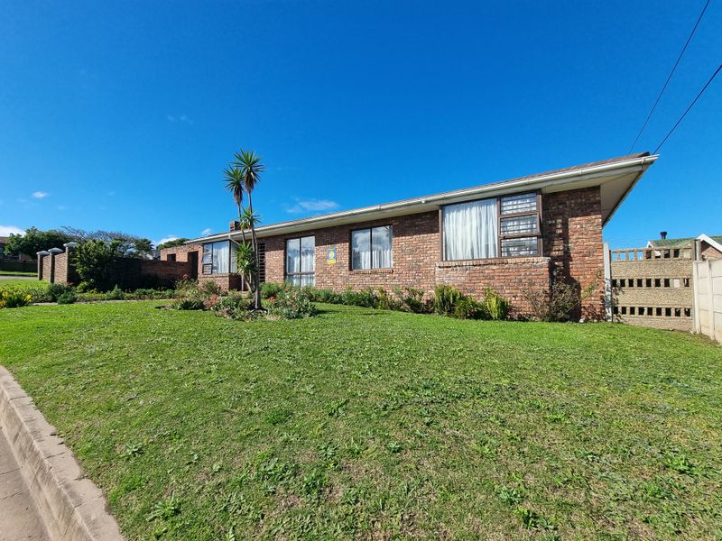 A well-maintained single-story face-brick house featuring large windows and a spacious front lawn, set behind a secure precast boundary wall.