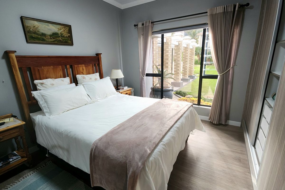 A well-maintained bedroom featuring laminate flooring, a built-in wardrobe, and a sliding glass door providing access to the garden area.