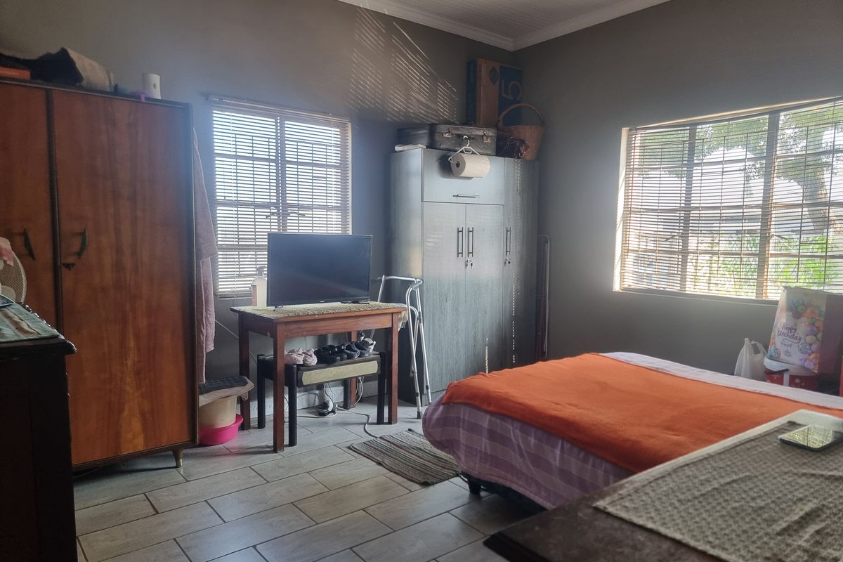 A bedroom featuring tiled flooring and venetian blinds, offering a functional space with natural light.