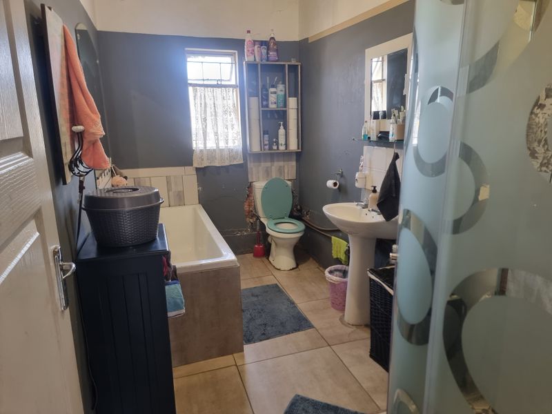 A functional bathroom featuring a bathtub, pedestal basin, and toilet, currently requiring cosmetic updates and repairs to the wall finishes.