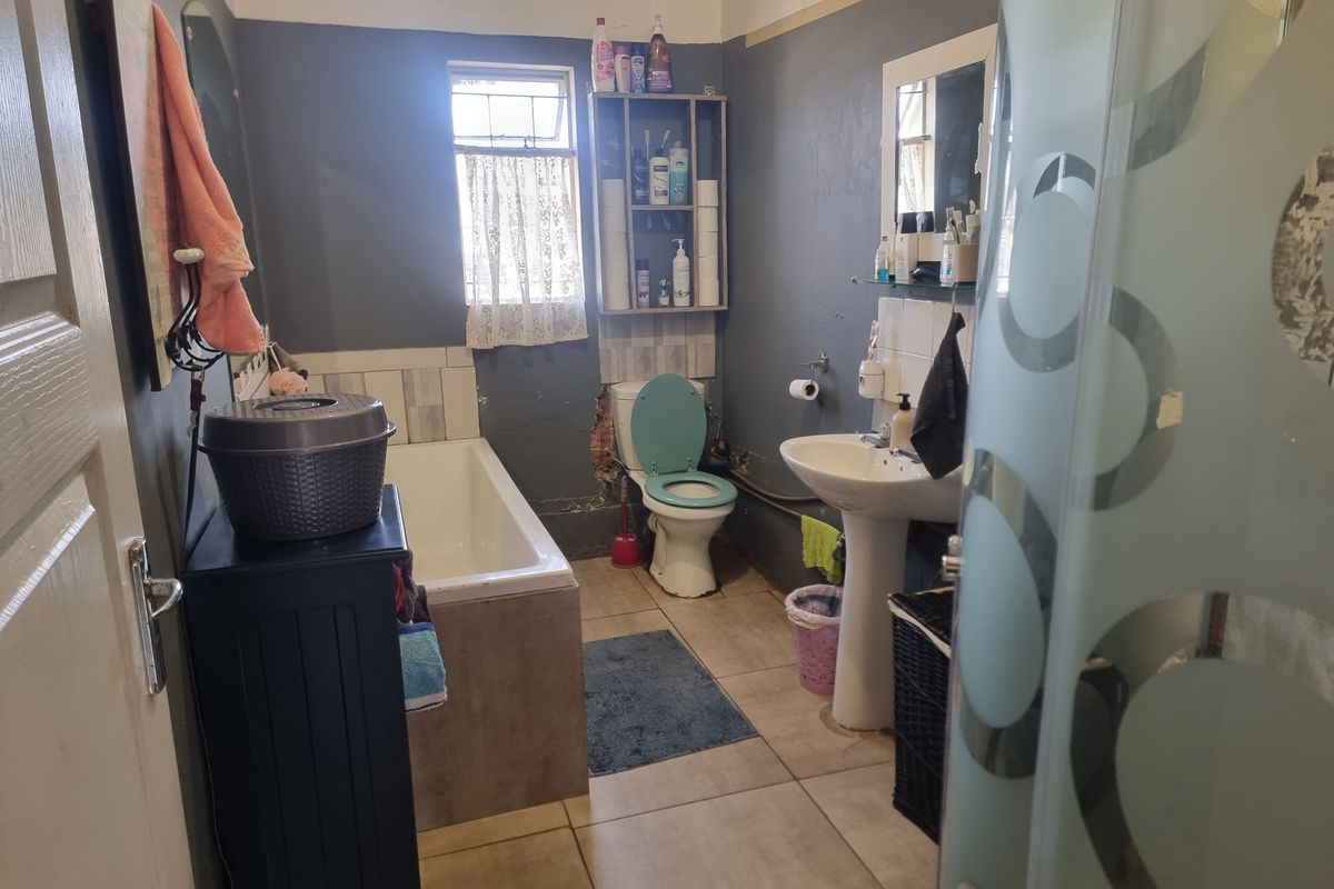 A functional bathroom featuring a bathtub, pedestal basin, and toilet, currently requiring cosmetic updates and repairs to the wall finishes.